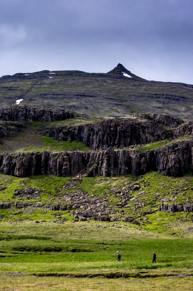 two person walking on green grass field with mountain