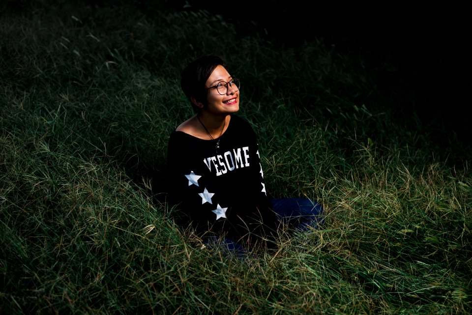 woman sitting on grass smiling and looking up during nighttime