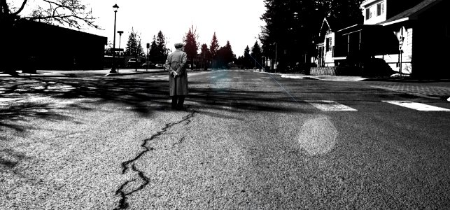 man standing in the middle of the road grayscale photography photo