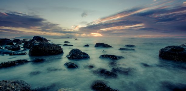 ocean waves crashing on rocks during sunset photo