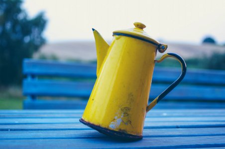 yellow kettle on gray wooden table photo