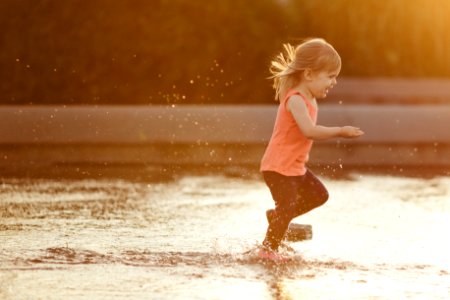 girl in pink tank top and brown shorts running on water during daytime photo