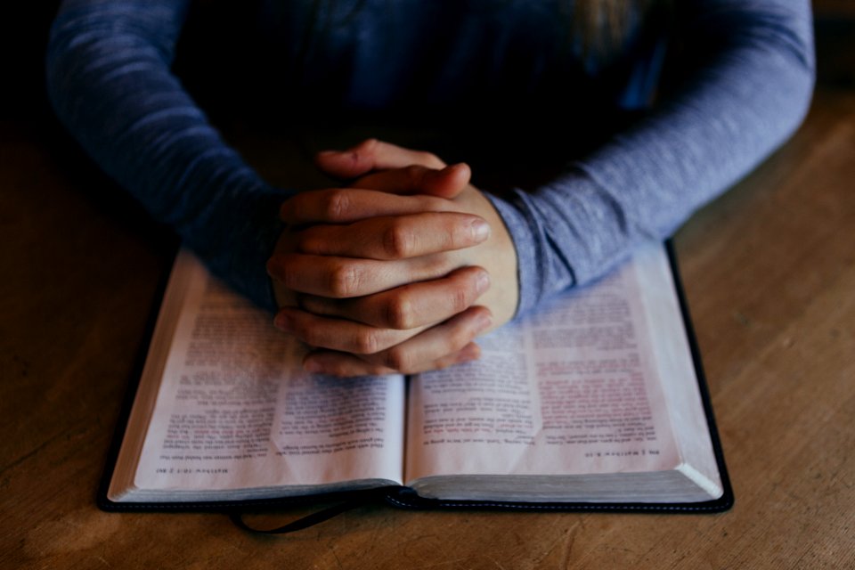 man holding his hands on open book