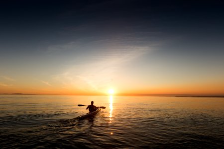 man riding kayak on water taken at sunset photo