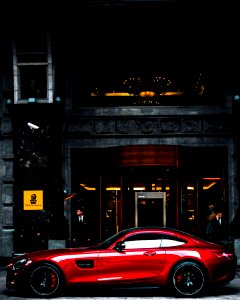 red coupe parked in front of black and gray building during daytime photo