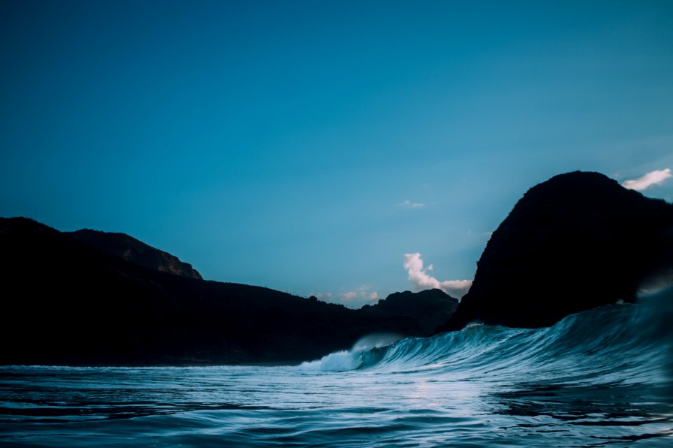 body of water near mountains at nighttime