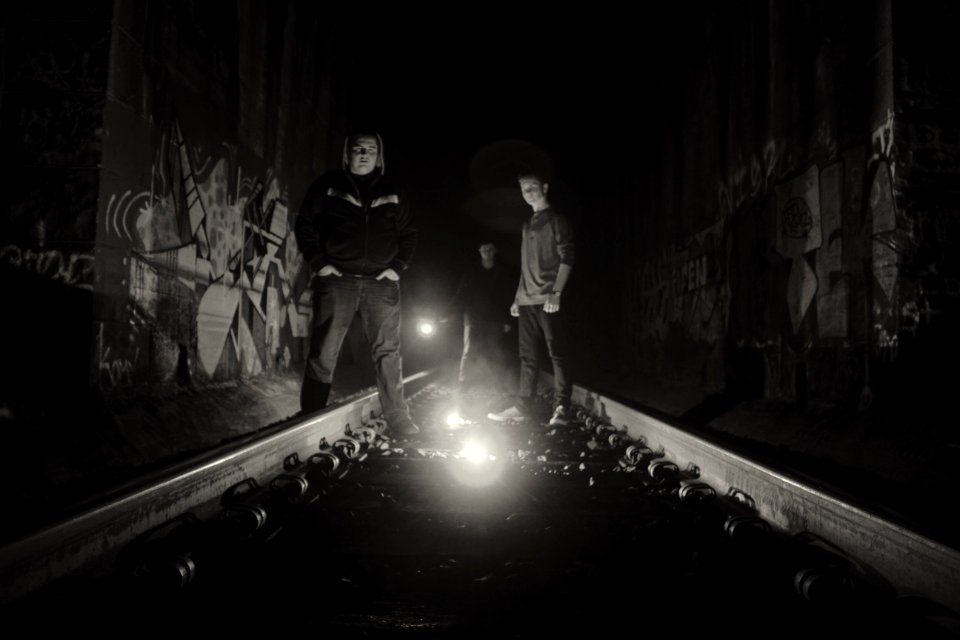 grayscale photography of two person standing on train rails