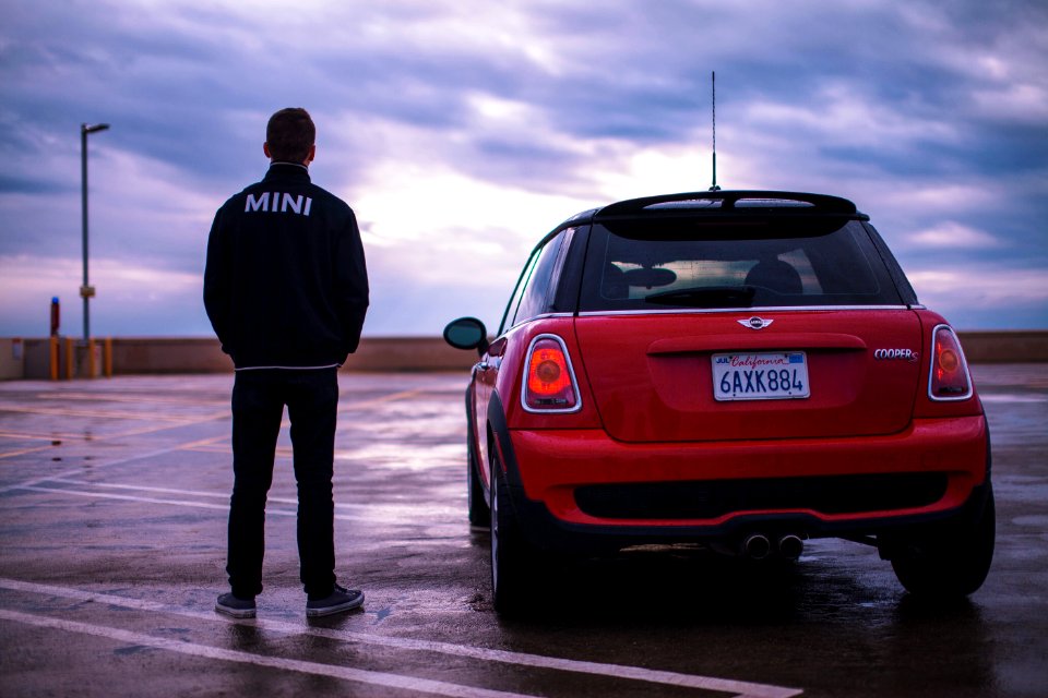 man standing red Mini vehicle during daytime