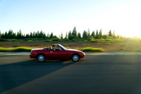 panning photography of man in red convertible photo