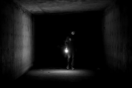 grayscale photography of person walking on tunnel