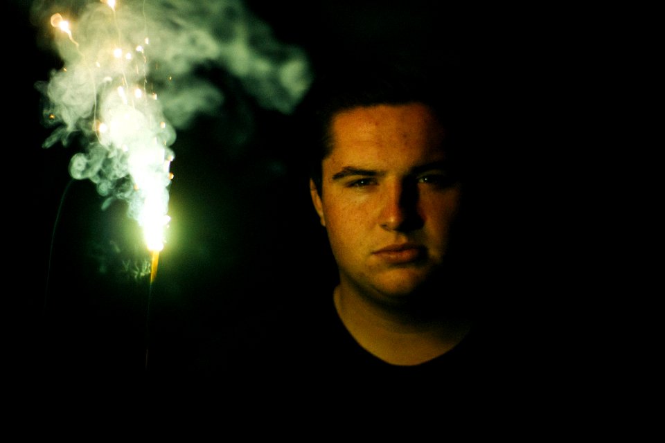 man wearing black crew-neck shirt holding sparkler