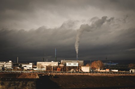 gray building with smoke under white clouds photo