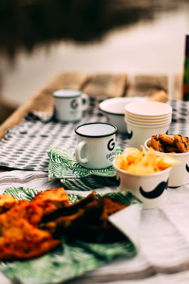 enamel-coated mugs and plastic cups on table selective focus photography