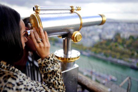 woman looking through a telescope during daytime photo