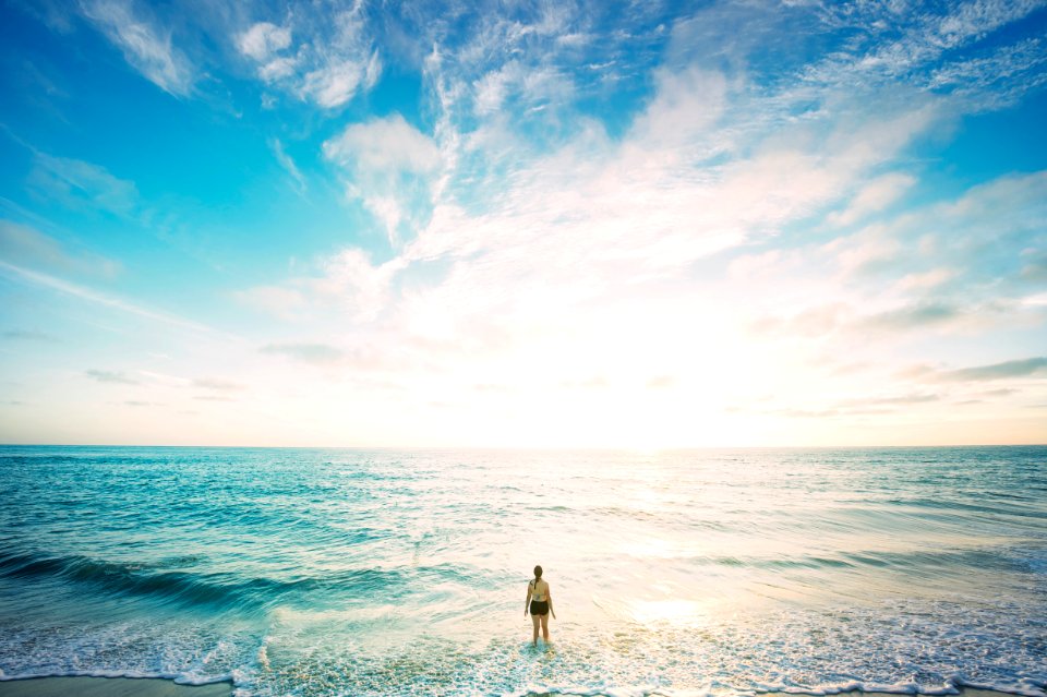 woman on sea in front of sun