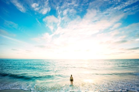 woman on sea in front of sun