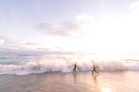 two person running on seaside beach during daytime photo
