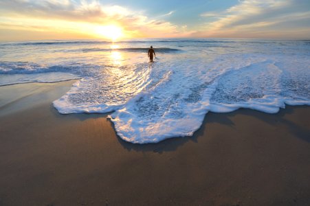 man standing on seashore during sunset photo