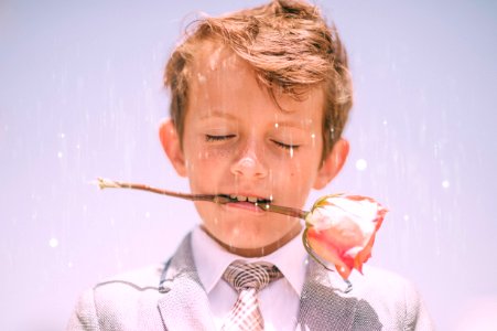 boy biting stem of pink rose