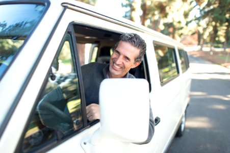 man in gray sweater leaning on van window