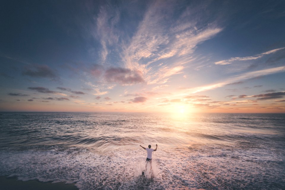man standing on seashore during sunset