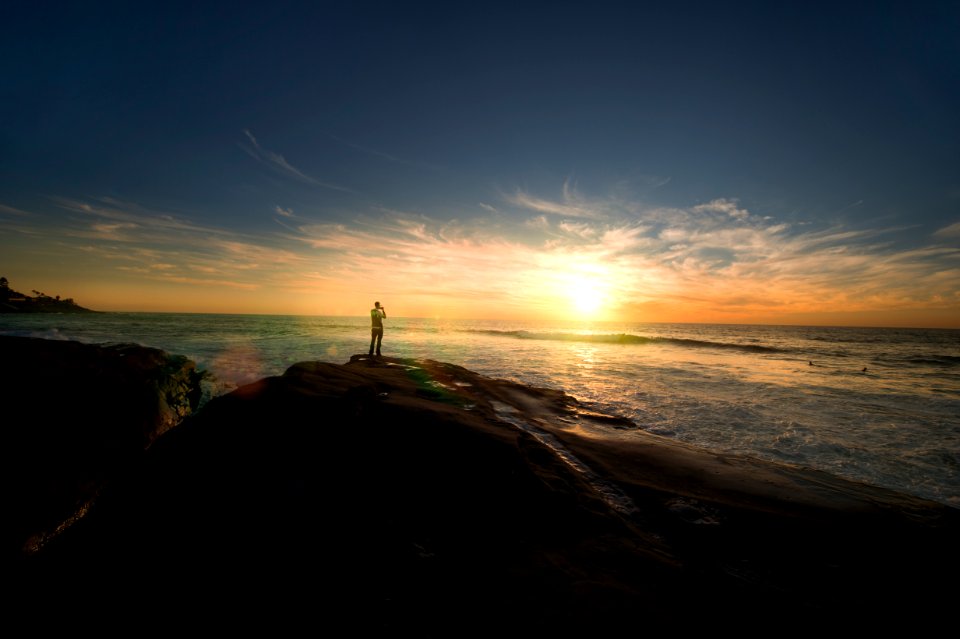 person standing on mountain facing sun at golden hour photo