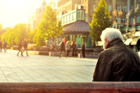 man sitting on brown wooden bench photo