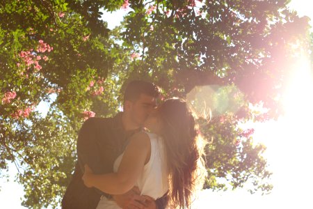 man kissing woman under green tree during daytime photo
