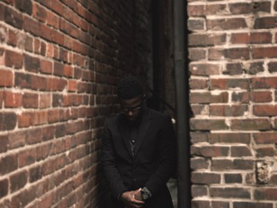 man in black suit standing on corner during daytime photo