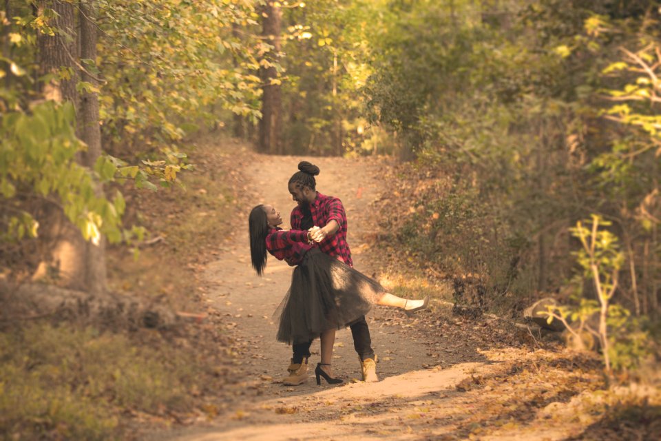 A couple standing in a nature trail embracing each other.