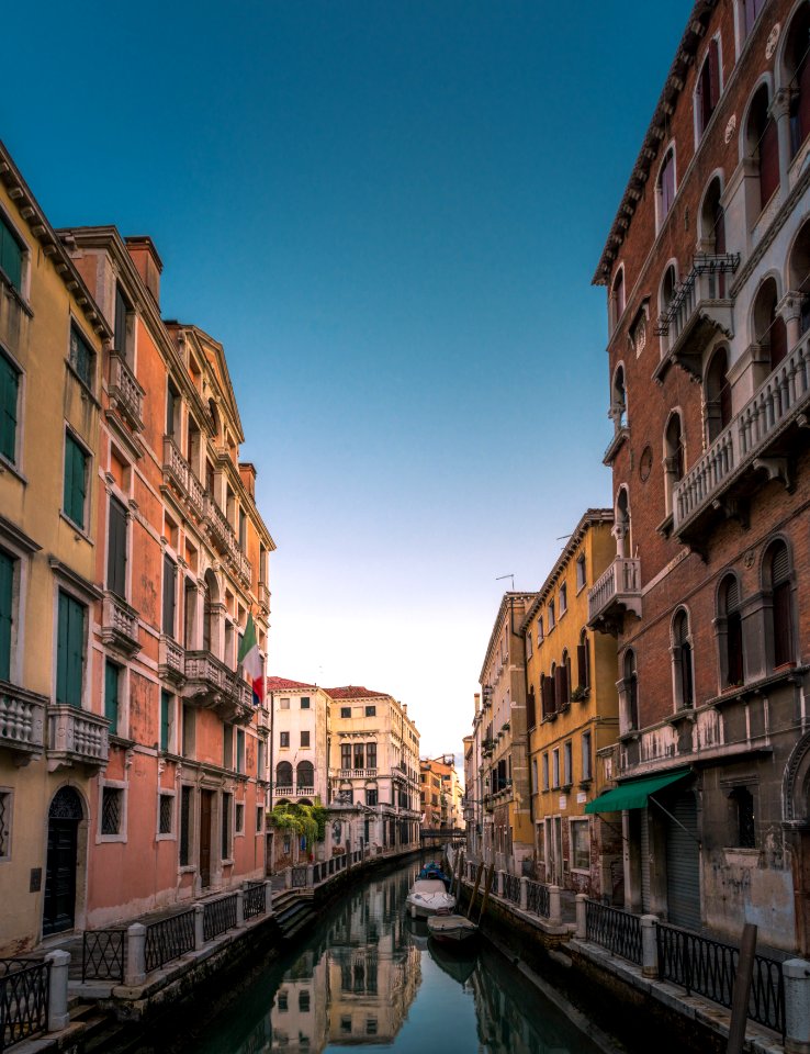 white boat on body of water between buildings