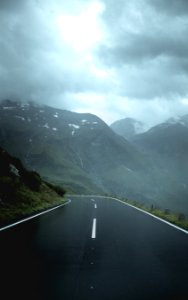 gray concrete road between green mountains under white clouds during daytime photo