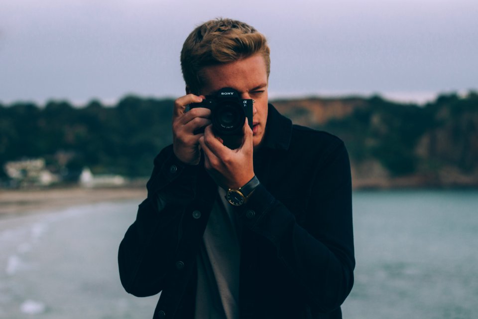 shallow photography of man holding camera