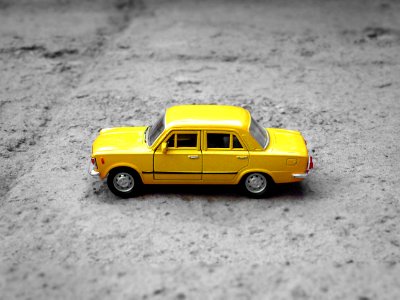 yellow sedan die-cast on gravel photo