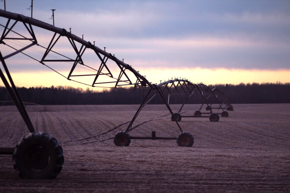 photo of black farming equipment under white clouds at daytime