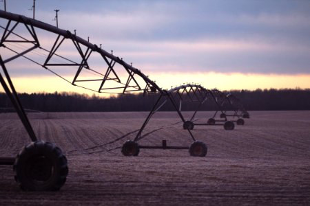 photo of black farming equipment under white clouds at daytime