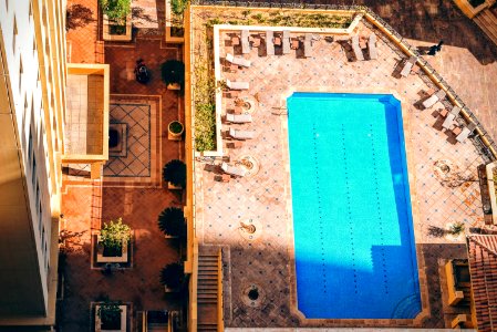 aerial photography of pool surrounded with sunlounger chairs near building photo