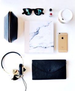 A flatlay image of paper, a smartphone, cup of coffee, glasses and various other items. photo