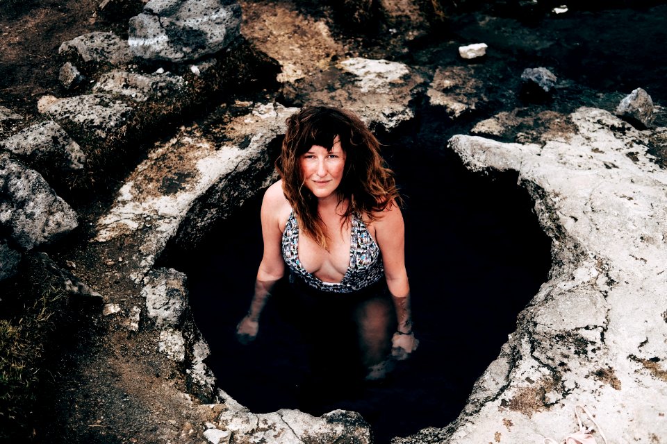woman in cave wearing one-piece swimsuit looking upward