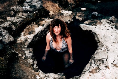 woman in cave wearing one-piece swimsuit looking upward photo