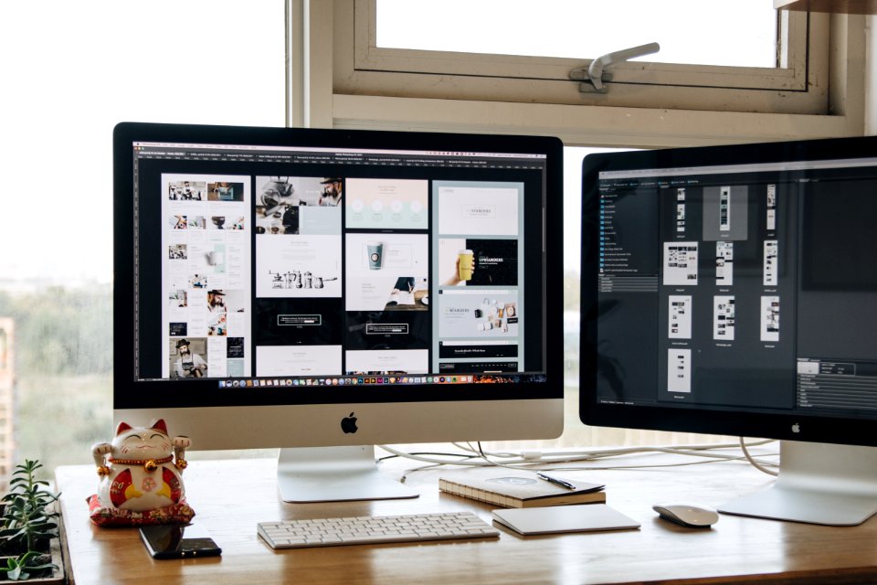 Two monitors setup next to each other on a computer desk. photo