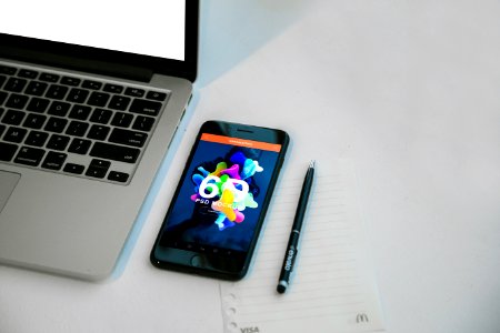 A smartphone next to a pen and laptop. photo