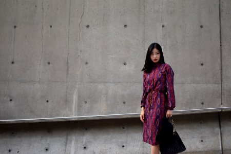 woman holding bag standing beside wall photo