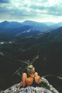 woman sitting next to cliff during daytime photo