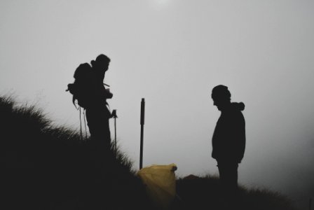silhouette photo of two men climbing mountain photo