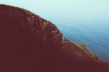 photo of cliff near calm sea during daytime photo