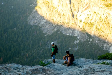 two men standing on rocky mountain cliff photo