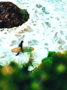 man on beach carrying surfboard photo