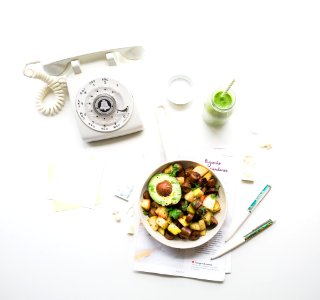 sliced avocado fruit inside bowl near rotary phone beside jar photo