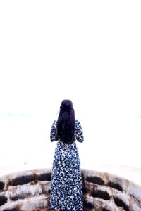 woman wearing black and white long sleeve dress standing facing sea during daytime photo